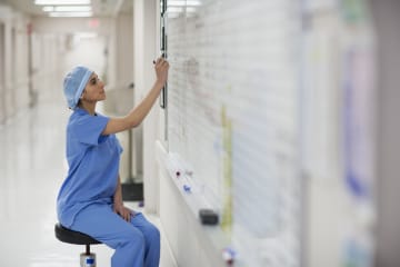 nurse writing on whiteboard in hospital