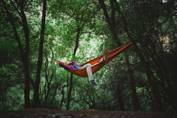 Young male rests on a hammock in the middle of the forest - stock photo