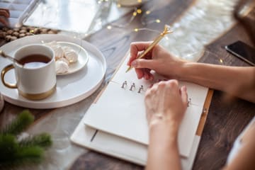 Young woman sitting with coffee and journaling her goals