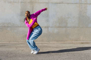 Woman breakdancing in front of wall - stock photo