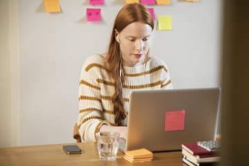 Female editor sitting at a desk with her laptop and notes