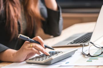 woman's using a calculator and working on laptop