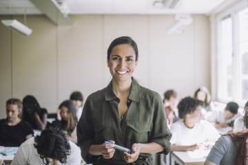 female teacher smiling while students study behind her