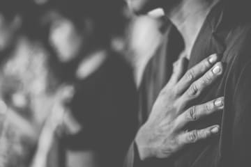 Man in suit with his hand over his heart in prayer.