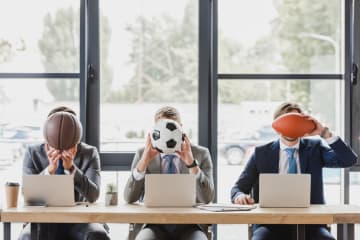 Three office workers holding different sports balls in their hands