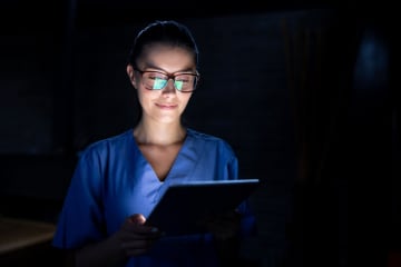 Portrait of a Latin American nurse looking at the results of a medical exam at night on a tablet - healthcare and medicine concepts