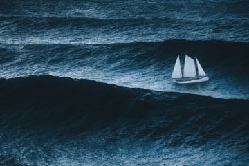 White sailboat sailing on large waves