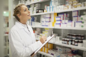 Pharmacist writing on clipboard - stock photo