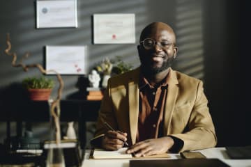 Male professional at desk with degrees on wall