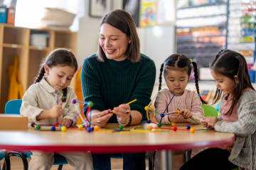 Teacher smiling while helping students in classroom