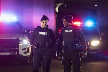 Police officers talking and walking near police cars