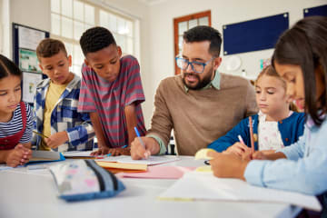teacher sitting and teaching young students