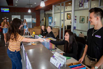 Student handing a paper to a person sitting down to apply to GCU.