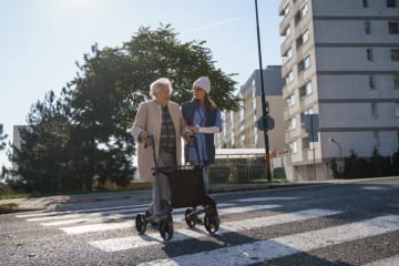 girl helping older woman across the street