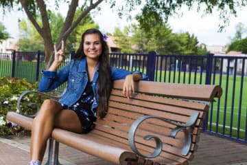 Tatum sitting on a bench on campus