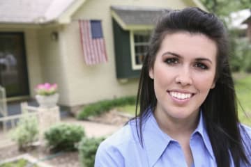 Beautiful woman in front of a house with an American flag floating