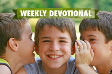 Students whispering to each other under the weekly devotional banner