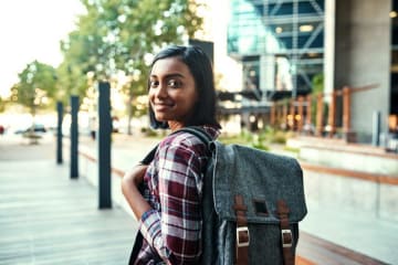woman holding a backpack looking back at the camera