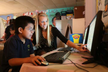 Teacher helping young boy with the computer