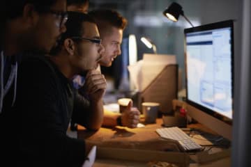 three men looking at a computer