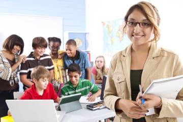 teacher smiling and students working in the background