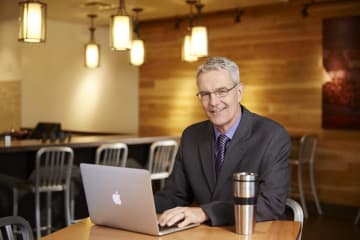 Doctoral student studies in cafe setting on laptop