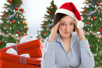 A woman in a Santa hat rubbing her temples in front of a Christmas tree