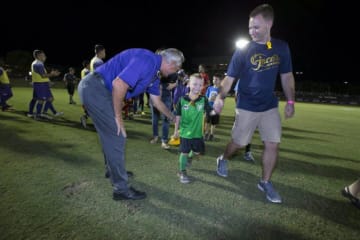 GCU's soccer team playing ball with a 10-year-old boy