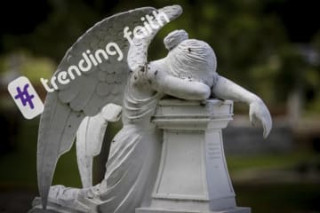 A statue of an angel in mourning under the Trending Faith logo