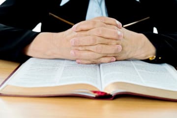A pair of hands folded over the Bible
