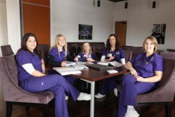 five nurses sitting around a table working