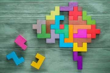 Colored puzzle pieces form a brain shape with a few missing pieces