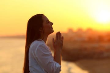 woman praying during sunrise or sunset