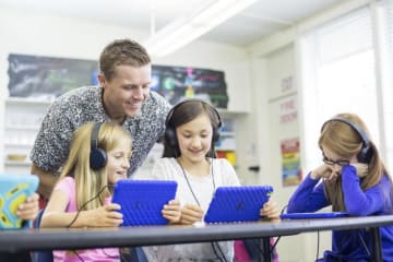 Teacher helping students with laptops