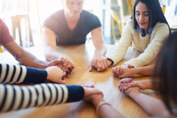 Group holding their hands together in prayer