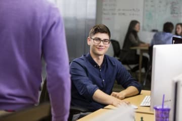 student sitting at a computer smiling