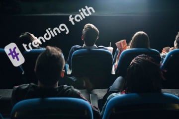 Back view of people seated in a movie theater looking at the front screen