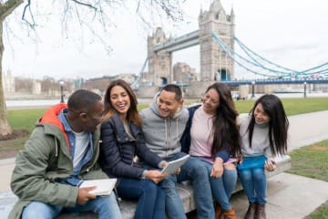 group of students sitting on bench in front of Tower Bridge in London