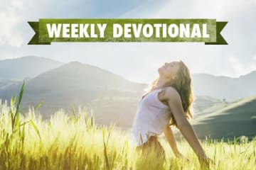 A joyful woman in a field under the Weekly Devotional banner