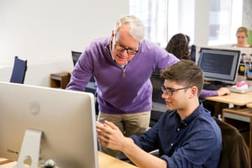 Programmer working at a computer with his professor