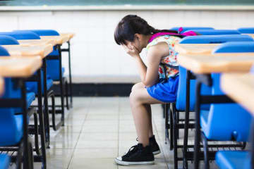 kid sitting in a classroom with head in hands