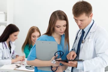 Nurse looking at a screen in doctor's hands