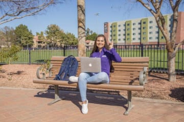 Tatum sitting on a bench on campus
