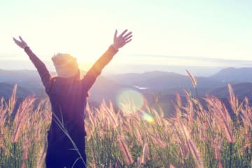 woman with arms raised in an open field