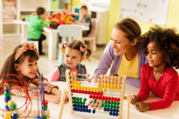 children playing in a classroom with an adult