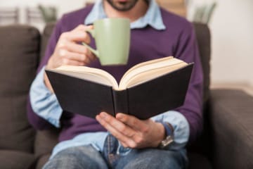 A man reading a book with a cup of coffee