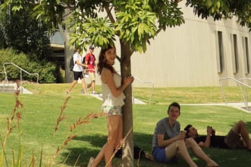 Kaitlyn poses by a tree with another international student