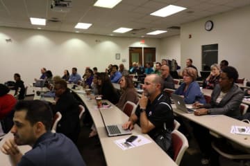 Adult students sit in class paying attention to the front of the classroom