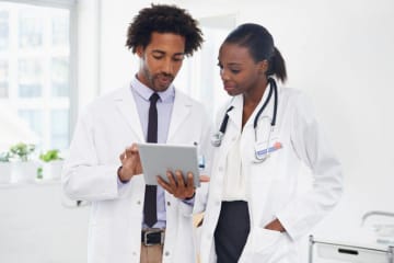 Two African-American doctors review results on tablet