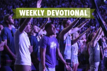 A group of students worshiping at Chapel under the Weekly Devotional banner